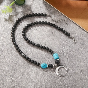 Detalle del collar bohemio de piedra de lava con toques turquesas y colgante de luna plateada