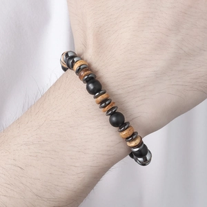 Detail van vintage houten kralen en zwarte lavasteen elastische armband om de pols