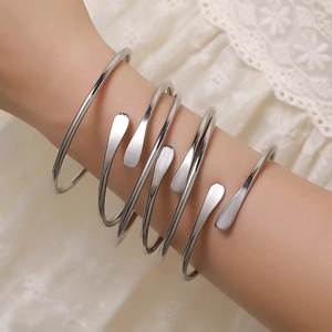 Detail of silver spiral metal arm cuff featuring sleek layered coils and leaf shaped ends