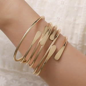 Detail of a layered golden metal upper arm cuff with unique flat teardrop ends