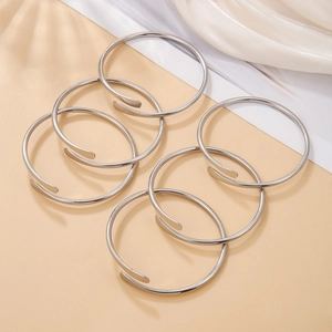 Detail of 6-piece silver metal open ring bracelets with polished finish on beige fabric