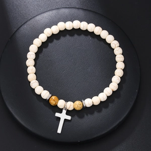 Detalle de pulsera de cuentas de turquesa blanca con textura de mármol y cruz colgante