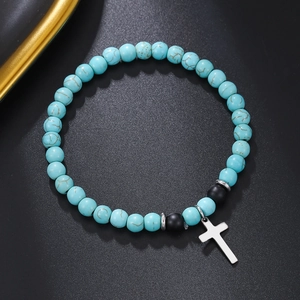 Detalle de una pulsera de cuentas turquesas bohemia con colgante de cruz metálica
