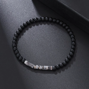 Detail of matte black beads and marble-patterned stones on a minimalist bracelet