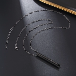 Detalle macro del collar silbato de acero negro con cadena ajustable y cierre de langosta