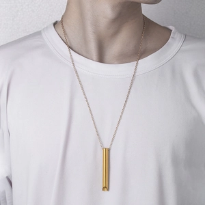 Collar de silbato de meditación de acero dorado sobre un modelo con camiseta blanca