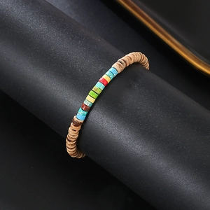 Macro view of woven bracelet with coconut wood beads and colorful natural emperor stones