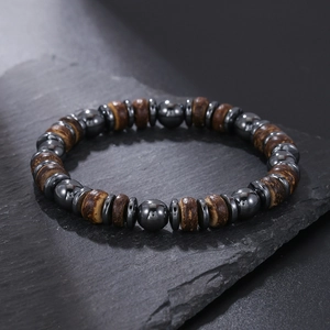Detailopname van kralenarmband met hematietstenen en donkere houttexturen