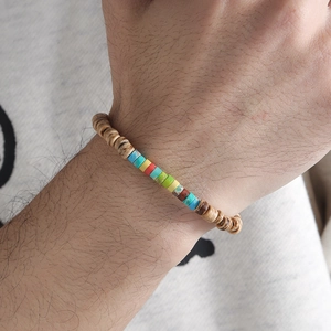 Close-up of handmade beaded bracelet with natural wood and colorful stone on wrist