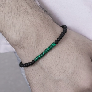 Detailed close-up of handmade beaded bracelet with black matte beads and green emperor stone