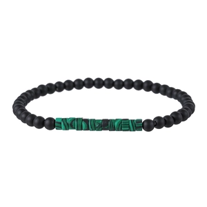 Detail of matte black beads and green malachite cylinders on beaded bracelet