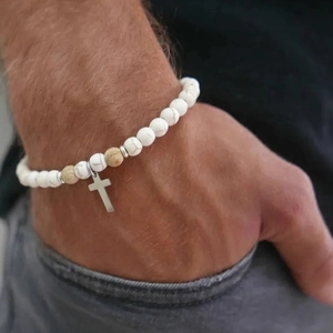 Pulsera bohemia de cuentas turquesas con colgante de cruz de plata en la muñeca