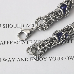 Macro shot of silver Byzantine chain with blue beads and lobster clasp detail