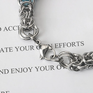 Macro detail of stainless steel braided bracelet with lobster clasp and blue bead accent