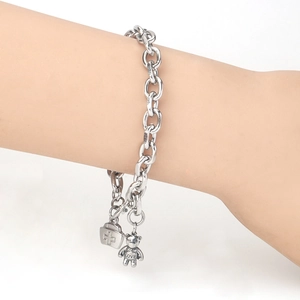 Detail of silver chain bracelet with teddy bear and nurse hat charms on a wrist