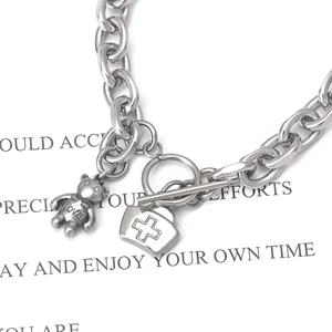 Close-up of stainless steel chain bracelet with bear and nurse hat charms and OT buckle