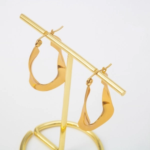Polished gold stainless steel twisted U-shaped hoop earrings for women on a display stand