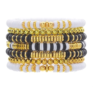 Detail of bohemian stackable bracelets with black and white heishi beads and gold beads