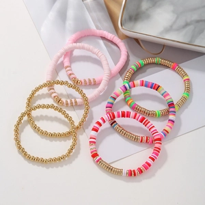 Detail of multi-layered bohemian stretch bracelets with pink clay beads and gold accents