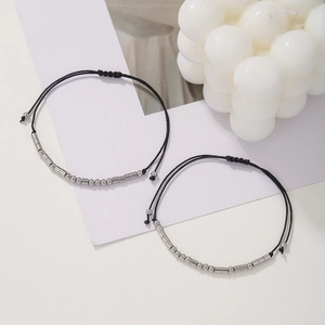Detailed view of Morse code bracelets with silver beads on black woven strings