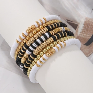 Close-up of black and white Heishi bead bracelets with golden metal spacers on display