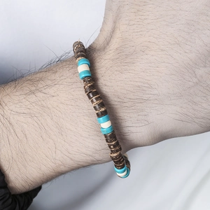 Detailopname van kralenarmband met donkere kokosnootschalen en turquoise accentkralen