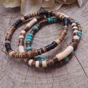 Set di tre braccialetti con perline di turchese e legno su sfondo in vero legno