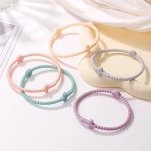Close-up of beaded silicone cross bracelets in pastel macaron colors on silk fabric