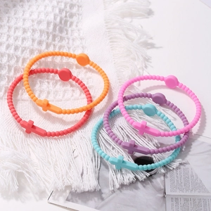Close-up of colorful silicone beaded bracelets with matching cross charms on soft fabric