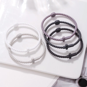 Detail of multi-color silicone beaded bracelets with cross charms on a white display tray