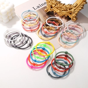 Colorful silicone macaron beaded bracelets with cross charms on a bright decorative desk