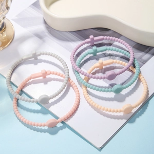 Detail of colorful macaron silicone bead bracelets featuring cross charms and round tags