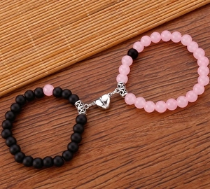 Dettaglio della chiusura magnetica a cuore tra bracciali di perle rosa e nere