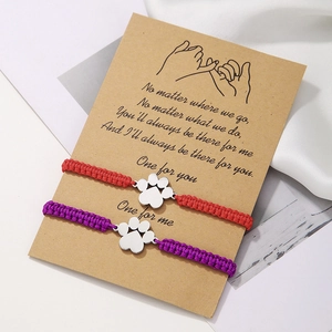 Détail de bracelets de couple tressés rouges et violets avec pendentifs patte de chien sur carte