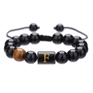 Detalle macro de la pulsera ajustable de ónix de 10mm con ojo de tigre y letra F en dorado