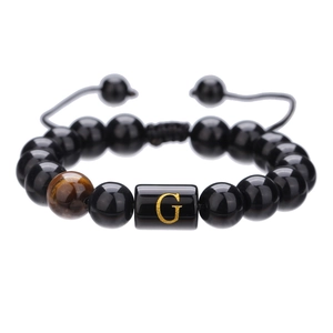Detalle de cuentas de ágata negra de 10mm y cuenta con letra G dorada en la pulsera ajustable