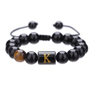 Detalle de pulsera de cuentas de ónix negro de 10mm con letra K dorada y cordón negro