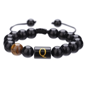 Primer plano de cuentas de ónix negro de 10mm con ojo de tigre y dije letra Q en cordón trenzado