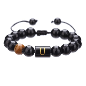 Detalle macro de pulsera de cuentas de ónix de 10mm con ojo de tigre y letra U dorada