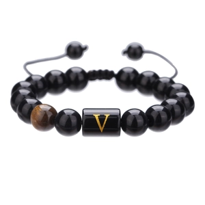 Vista macro de pulsera ajustable de cuentas de ónix negro con pieza de letra V dorada