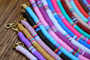 Close-up of handmade bohemian colorful heishi clay bead necklaces with lobster clasps