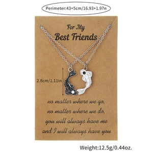 Detailed view of yin yang koi fish necklaces on a card showing matching black and white pendants