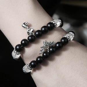 Gros plan de bracelets gothiques en perles noires mates avec breloques renard et chauve-souris
