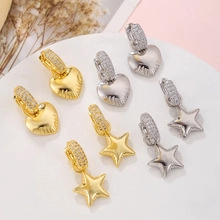Close-up of heart and star gold plated earrings with zircon paving on a white tray