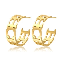 Macro detail of gold plated hoop earrings featuring hollow letter engraving and polished finish
