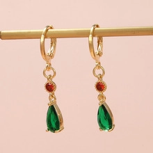 Detailed view of luxury gold-plated drop earrings with red round and green pear stones