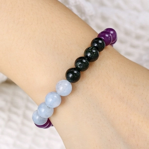 Nahaufnahme von lila und schwarzen Vulkansteinperlen am elastischen Armband am Handgelenk