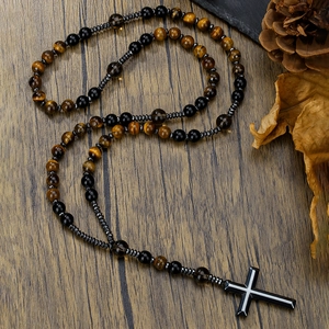 Detail van kralenketting van natuursteen met zwarte kruishanger op houten ondergrond