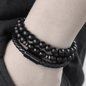Close-up of triple-layered black bead and woven leather bracelets with magnetic clasp