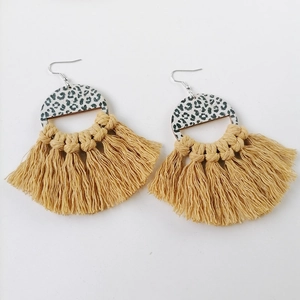 Detail of mustard yellow tassel earrings with leopard print accents and wooden semi-circle